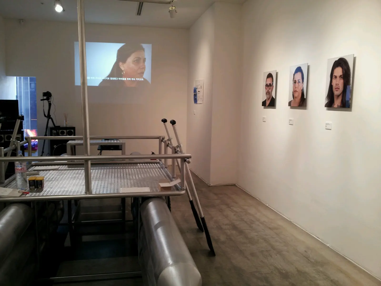 Installation view with the raft installation, portrait photographs of the Bussot family, and the interview video arranged together in one space.