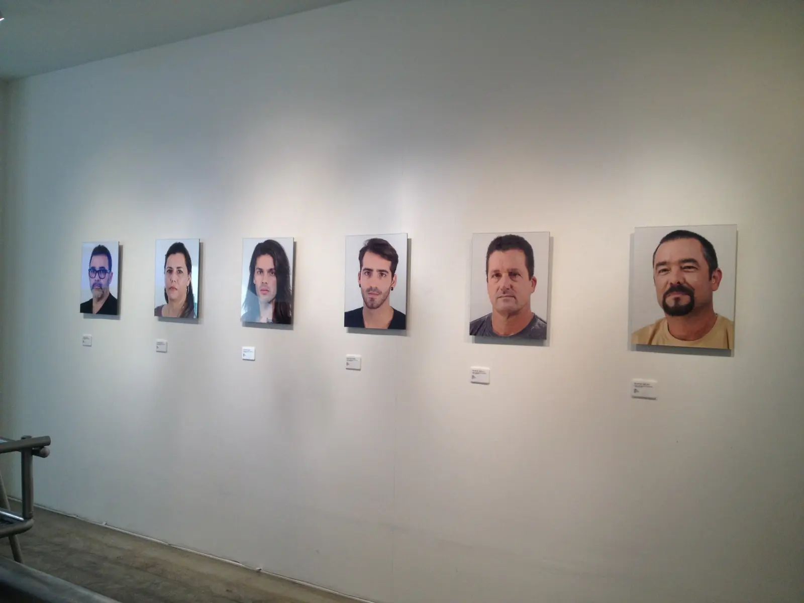 Exhibition wall displaying portrait photographs of the Bussot family and those who shared the voyage.
